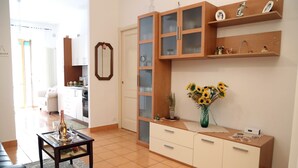 Un saló amb un sofà, una taula de centre, un armari amb portes de vidre i un vas amb girassols.