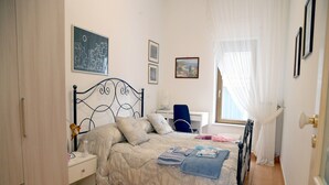 Un dormitori amb un llit, escriptori, cadira i armari.