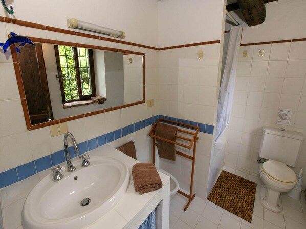 Un baño con lavamanos, espejo, toallero, inodoro y cortina de ducha.