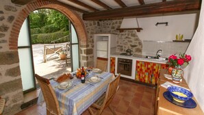 Una cocina rústica con pared de piedra, vigas de madera y suelo de baldosas.