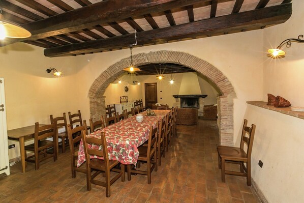 Un comedor con una mesa larga, sillas de madera y una chimenea de ladrillo.