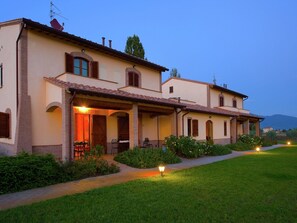 A two-story house with a covered patio and a well-maintained lawn.