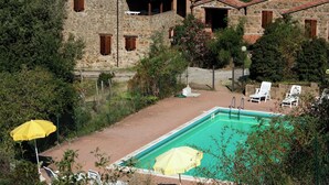 Uma villa de pedra com piscina, rodeada por vegetação e com vista para uma paisagem montanhosa.