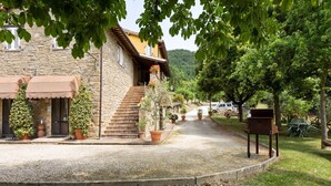 A stone building with a gravel driveway, potted plants, and outdoor seating.