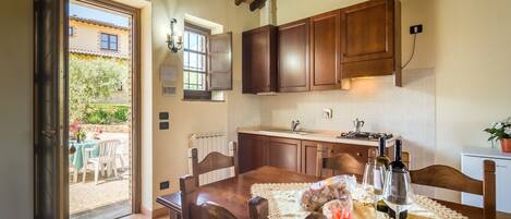A kitchen with wooden cabinets, a dining table with chairs, and a view of the outside.