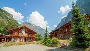 A traditional wooden chalet with a stone facade, set in a mountainous area with a cobblestone courtyard. - Apartment in Antey with Stunning Mountain Views (Antey st. Andre)