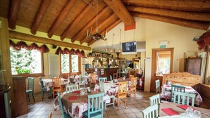 A restaurant with wooden beams, tiled floor, and tables with white and red tablecloths. - Apartment in Antey with Stunning Mountain Views (Antey st. Andre)