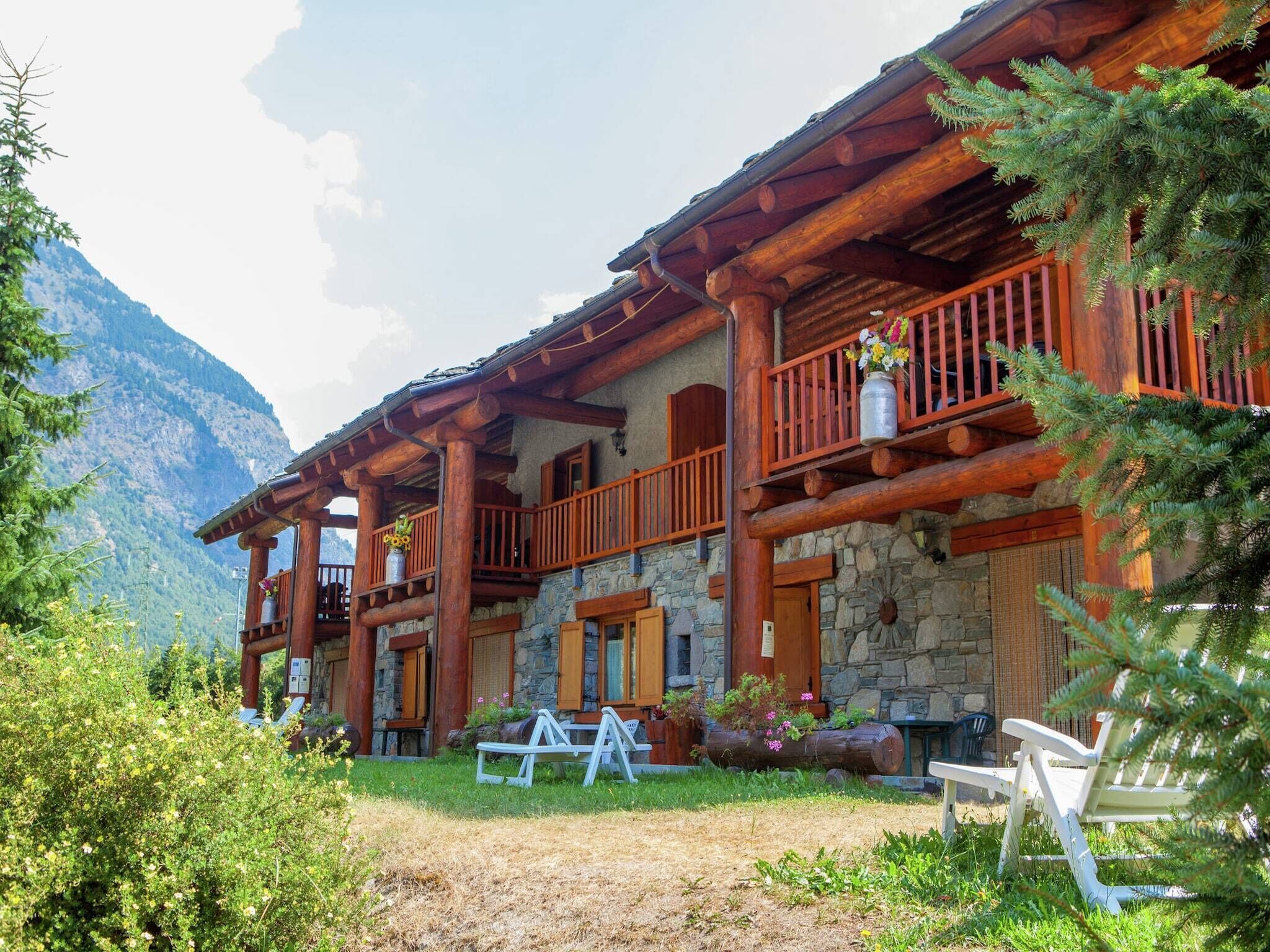 Une cabane en rondins dotée de plusieurs balcons, de murs en pierre et surplombant un paysage montagneux.