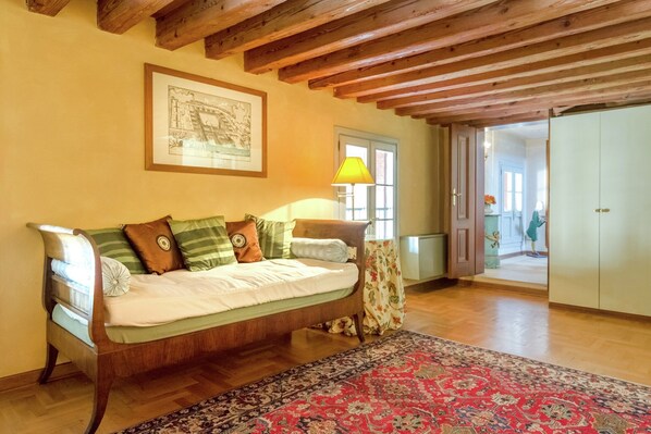 A cozy room with a wooden sofa, a patterned rug, and a framed picture on the wall.