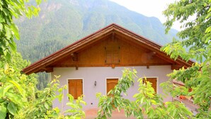 A mountain lodge with a wooden facade, two wooden doors, and a sloped roof.