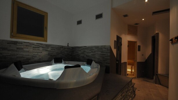 A spa area with a hot tub, stone wall, and a staircase leading to another room.