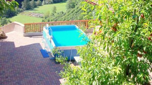 A swimming pool with a wooden deck and a view of a forested valley.
