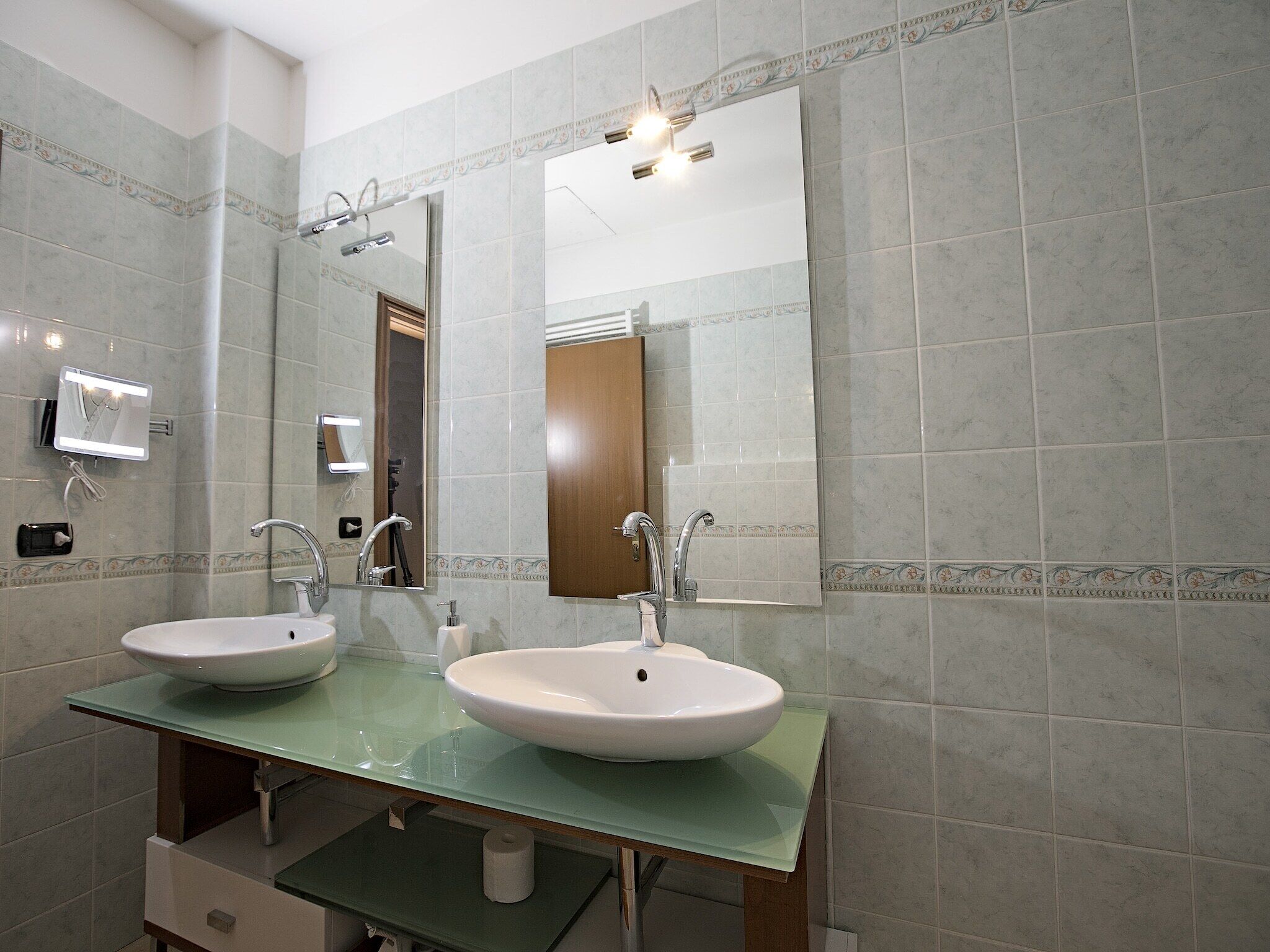 Un baño con dos lavamanos, un espejo y un dispensador de toallas.