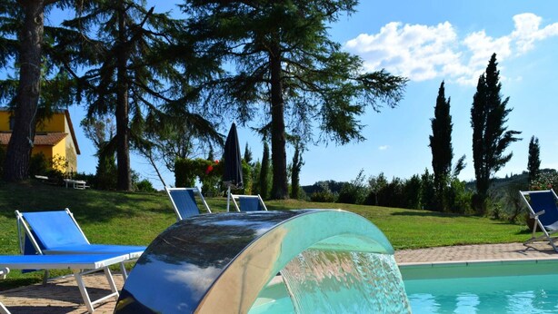 A swimming pool with a water slide, surrounded by lounge chairs and trees. - Holiday Home in Tuscany with Pool & Garden (Vinci)