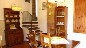 A dining area with a wooden table, chairs, and a chandelier. There is a staircase with a railing leading to another level. - Holiday Home in Tuscany with Pool & Garden (Vinci)