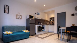 A compact living space with a kitchenette, a sofa, a dining table, and chairs.