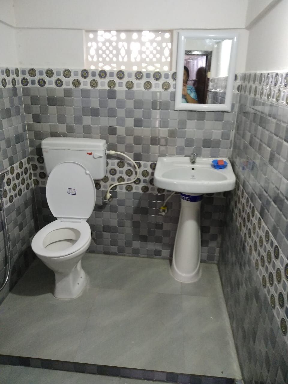 Ein kleines Badezimmer mit Toilette und Waschbecken, geflieste Wände und ein Spiegel über dem Waschbecken.