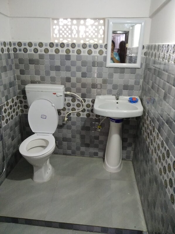 Ein kleines Badezimmer mit Toilette und Waschbecken, geflieste Wände und ein Spiegel über dem Waschbecken.