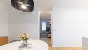 Ett modernt vardagsrum med ett runt bord, en vas med blommor och en stor, svart hänglampa.