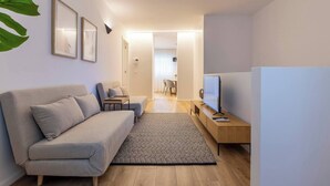Ett modernt vardagsrum med en grå soffa, en tv på ett träställ och ett litet bord.