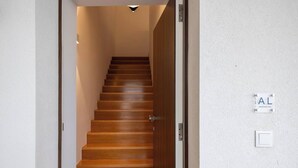 En trätrappa som leder upp till en liten plattform med en väggmonterad lampa och en skylt som visar var man kan hitta lokala boenden.