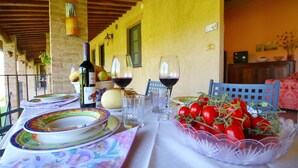 Une table à manger dressée avec des assiettes, des verres, une bouteille et un saladier de tomates.
