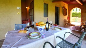 Une table dressée pour le repas, avec des assiettes, des verres et une bouteille de vin, entourée de chaises.