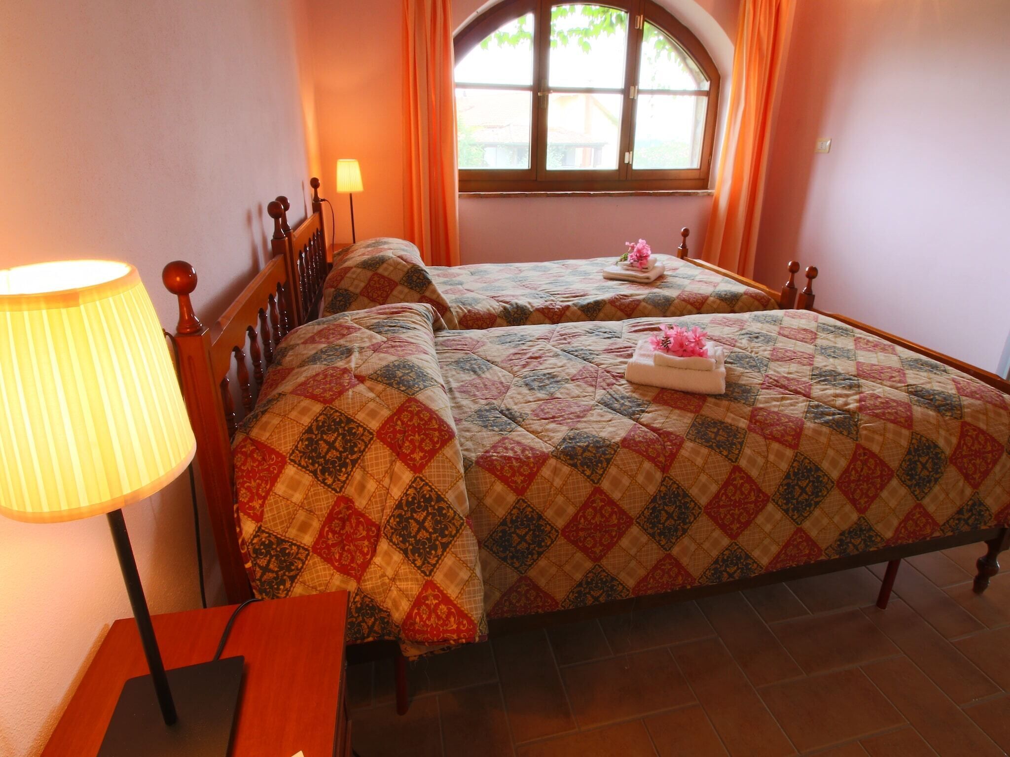 Un dormitorio con dos camas, una lámpara y un ventanal con cortinas.