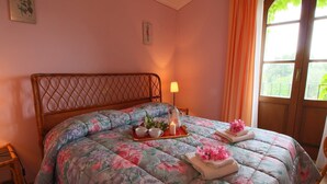 Una cama con edredón floral, una bandeja con vela y una lámpara.