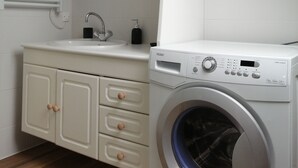 A laundry room with a front-loading washing machine, a sink, and a mirror. - Southern Brittany - peace and quiet by the sea (Noyal-Muzillac)