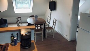 A compact kitchen with a coffee maker, a dining table with chairs, a window, and a wall-mounted TV. - Southern Brittany - peace and quiet by the sea (Noyal-Muzillac)