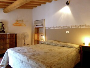 Une chambre à coucher comprenant un lit, une commode, un ventilateur et une lampe fixée au mur.