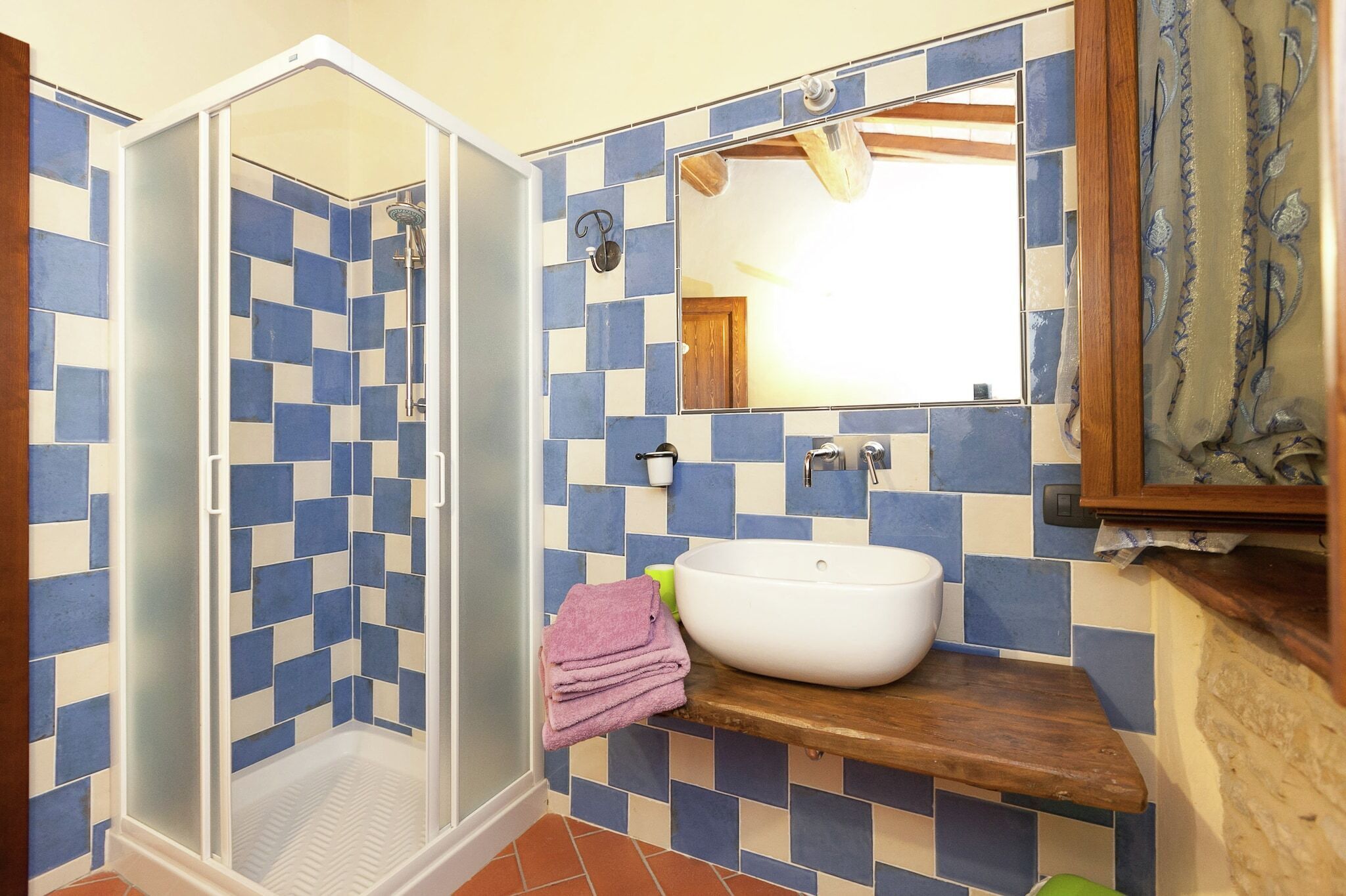 A bathroom with a shower, a sink, and a mirror.