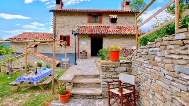A rustic stone house with a tiled roof, a wooden pergola, and a stone wall. - Farmhouse in Marche with Pool and Views (Mercatello sul Metauro)