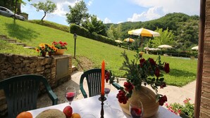 An outdoor dining area with a table set for two, featuring a candle, wine glasses, and fruit. - Apartment in Marche with Pool & Terrace (Apecchio)