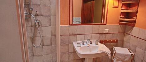 Un baño con ducha, lavabo y espejo.