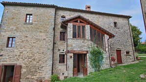 Un edificio de piedra con entrada central, varias ventanas y techo inclinado.