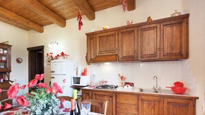 Eine Küche mit Holzausstattung, einer Mikrowelle und einem Spülbecken. Ein Tisch ist mit einer blumigen Tischdecke und einem Blumenstrauß dekoriert.