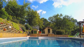 Ein klarer, blauer Pool mit einer Steinmauer und einem kleinen Gebäude im Hintergrund.