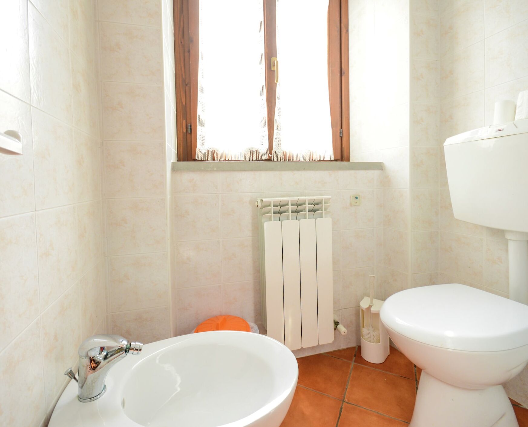 A bathroom with a white sink, toilet, and radiator.