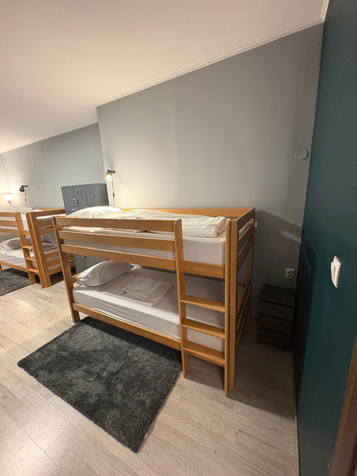 Een slaapkamer met stapelbedden, een grijs tapijt, een kledingkast en een bureau.