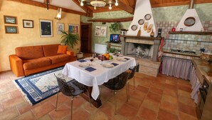 Uma área de refeições aconchegante, com teto de madeira, lareira e mesa posta para quatro pessoas.