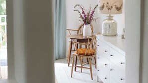 A room with a dining table and chairs, a vase with flowers, a lamp, and a white cabinet. - Stunning 3 bedroom Cottage on a private estate in SW Scotland (Mossdale)