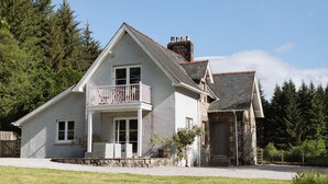 A two-story house with a balcony, a stone chimney, and a gravel driveway. - Stunning 3 bedroom Cottage on a private estate in SW Scotland (Mossdale)