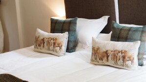 A bed with white bedding and four pillows featuring a lion print. - Stunning 3 bedroom Cottage on a private estate in SW Scotland (Mossdale)