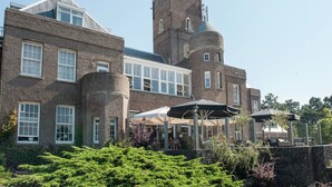 A large brick building with a tower, large windows, and outdoor seating areas. - Apartment in Bergen aan Zee near the Beach (Bergen aan zee)