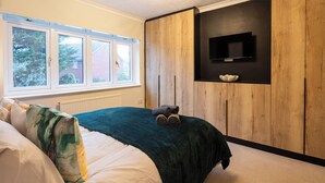 A bedroom with a bed, a window, a wooden wall, and a television mounted on the wall. - Cozy home in Bristol,Contractors, Relocation, Families, Parking, WIFI,SMARTTV (Bristol)