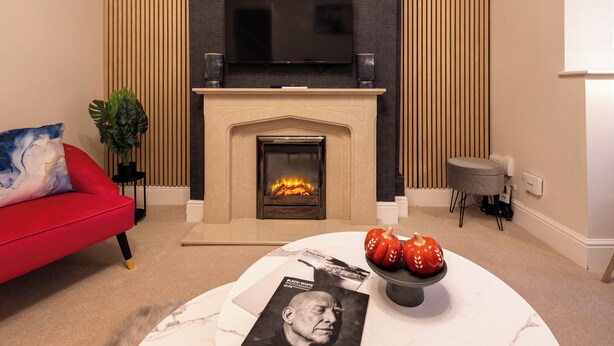 A modern living room with a fireplace, red sofa, and a coffee table with magazines and decorative items. - Cozy home in Bristol,Contractors, Relocation, Families, Parking, WIFI,SMARTTV (Bristol)