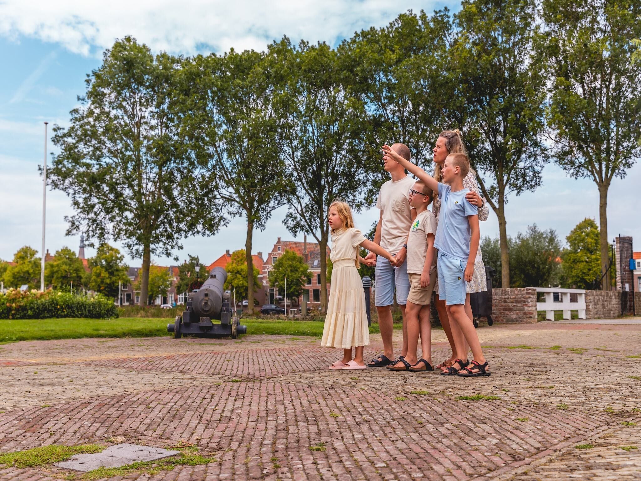 Un groupe de personnes se tient sur une surface pavée, avec un canon en arrière-plan.