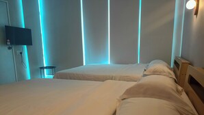 A hotel room with two beds, a TV mounted on the wall, and a small table. - Keteri Boutique Hotel (Kangar)